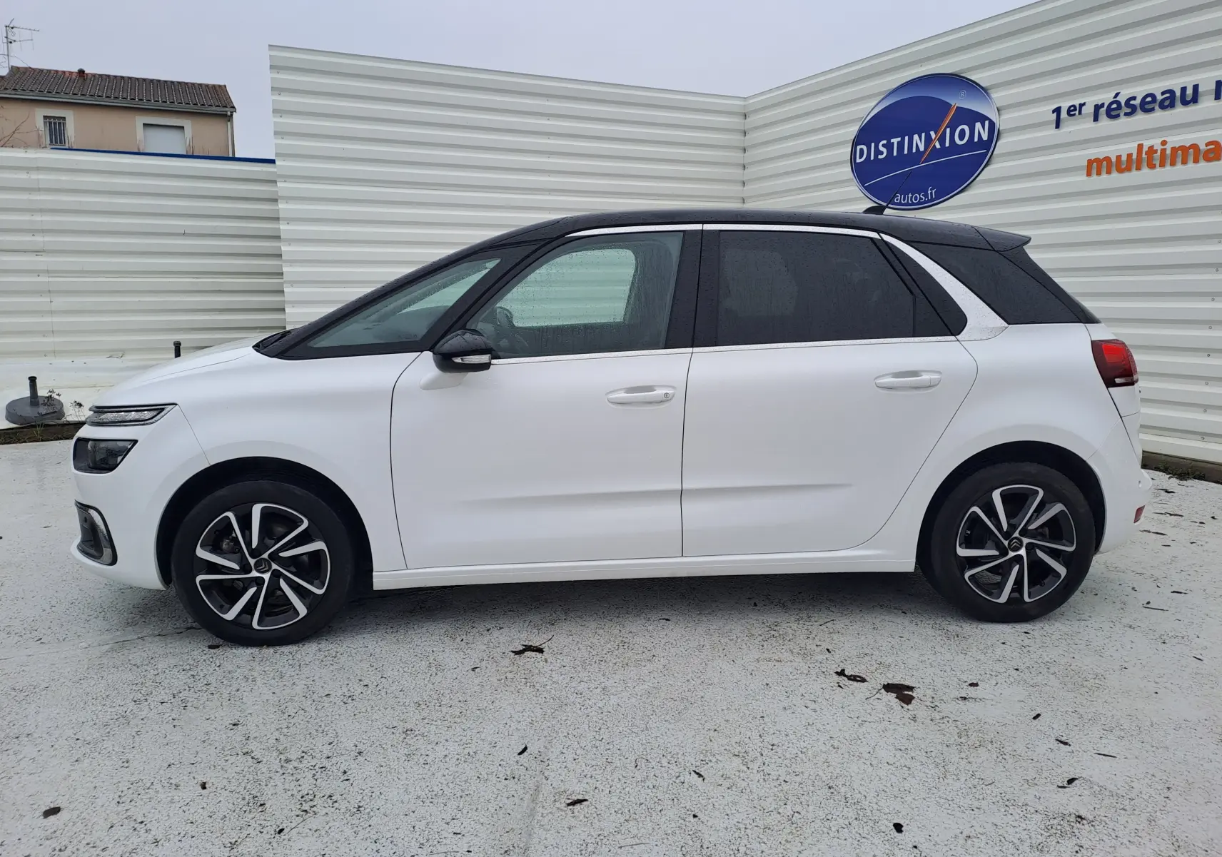 Vue de profil côté gauche d'une Citroën C4 Spacetourer blanche avec toit noir et jantes alliage bicolores.
