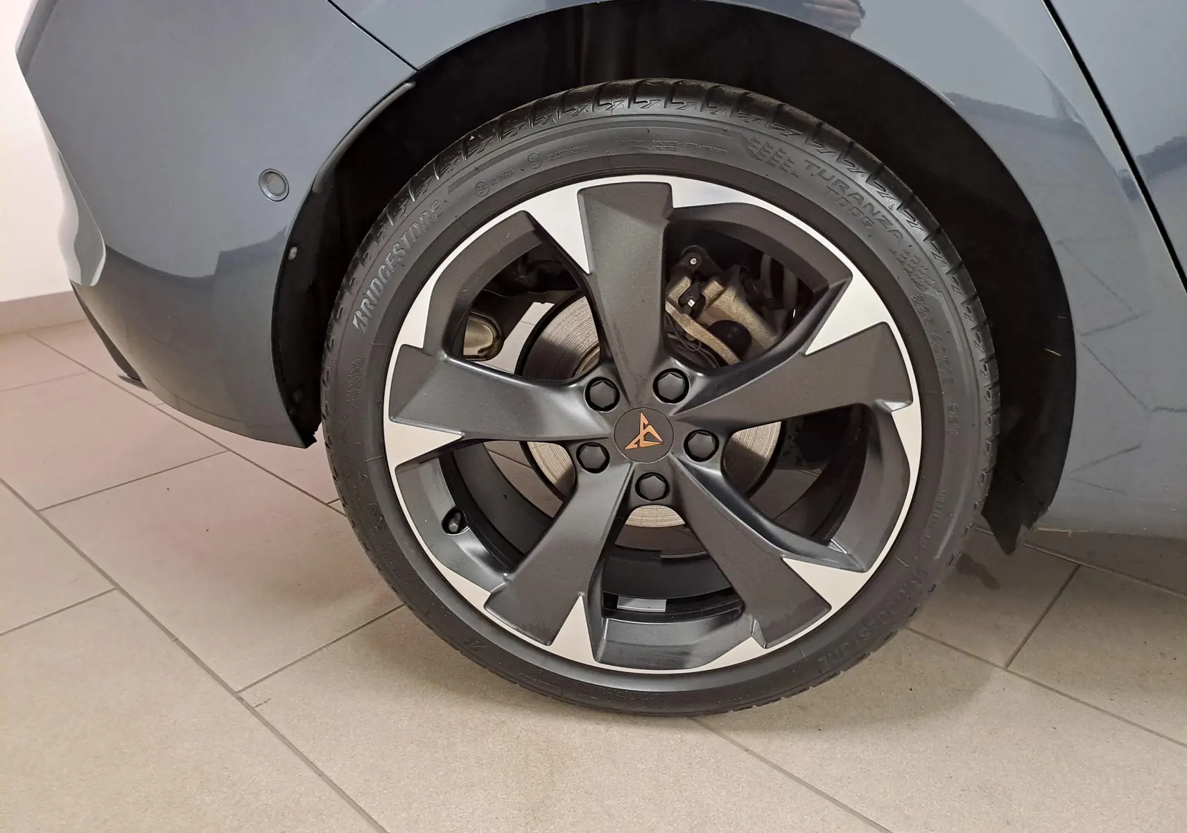 Gros plan sur la roue arrière droite de la CUPRA Leon 1.5 TSI 150 DS7 V gris magnétique avec jante alliage distinctive.