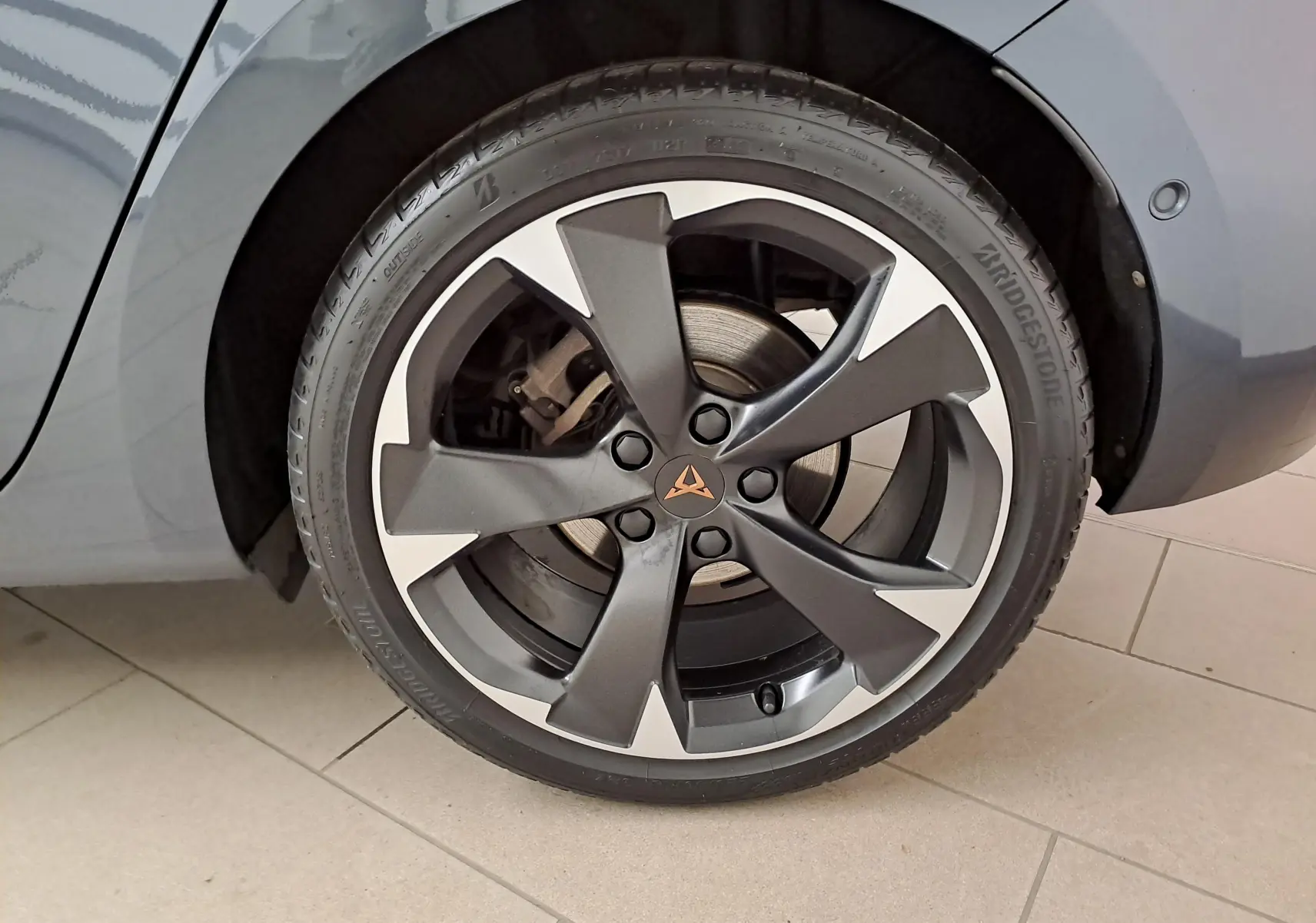 Gros plan sur la roue avant droite de la CUPRA Leon 2023 gris magnétique avec jante alliage bicolore et logo CUPRA central.