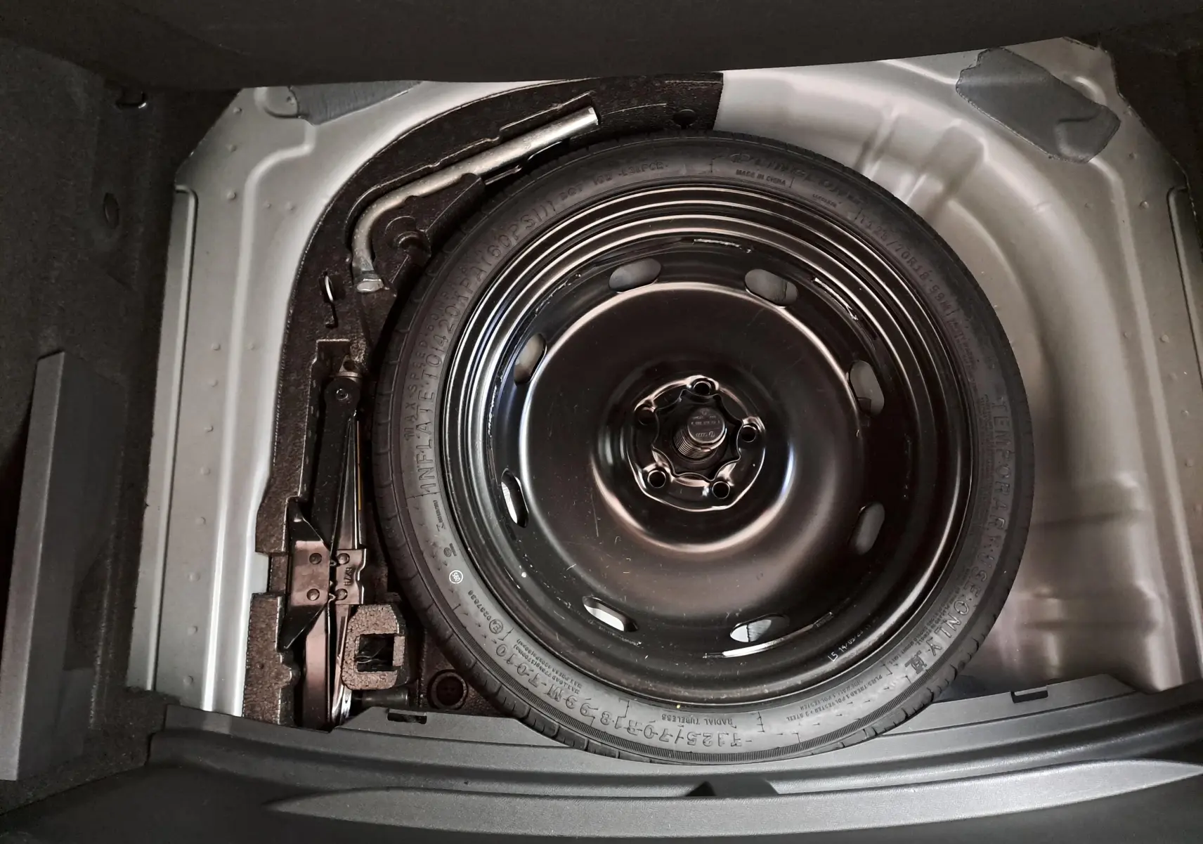 Roue de secours noire et outils de bord dans le coffre d'une CUPRA Leon 1.5 TSI 150 DS7 V 2023 gris magnétique.