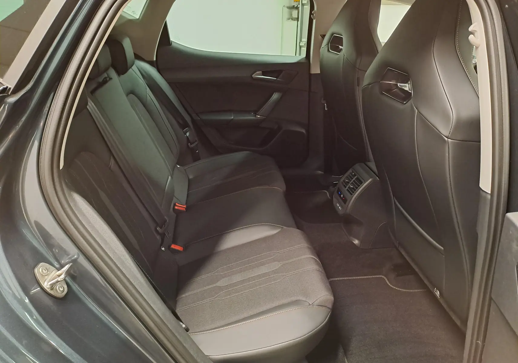 Vue intérieure côté gauche des sièges arrière en tissu et cuir noir d'une CUPRA Leon 1.5 TSI 150 DS7 gris magnétique 2023.