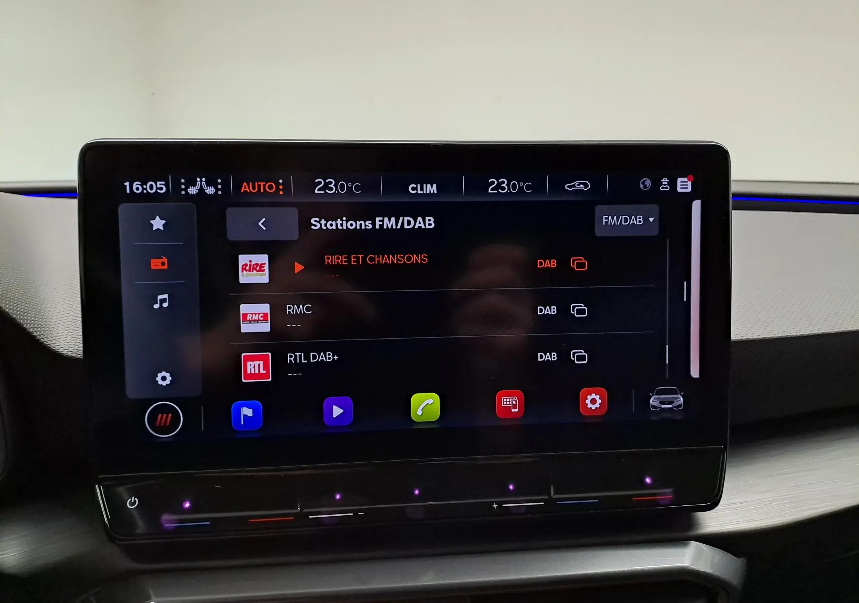 Écran tactile central de la CUPRA Leon 2023 affichant les stations FM/DAB avec interface moderne et commandes climatiques intégrées.