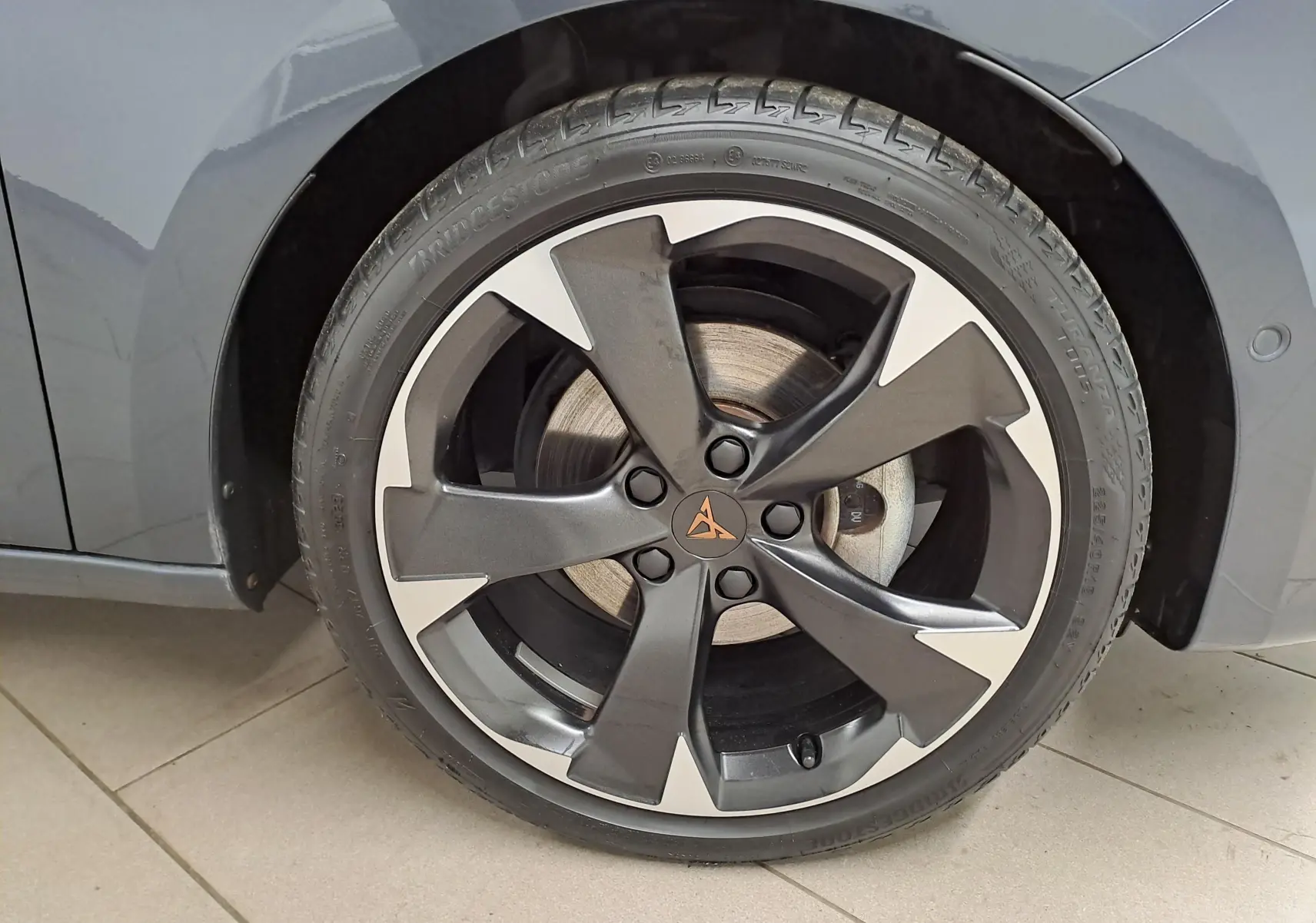 Gros plan sur la jante avant droite de la CUPRA Leon 1.5 TSI 150 DS7 V gris magnétique avec logo CUPRA central.