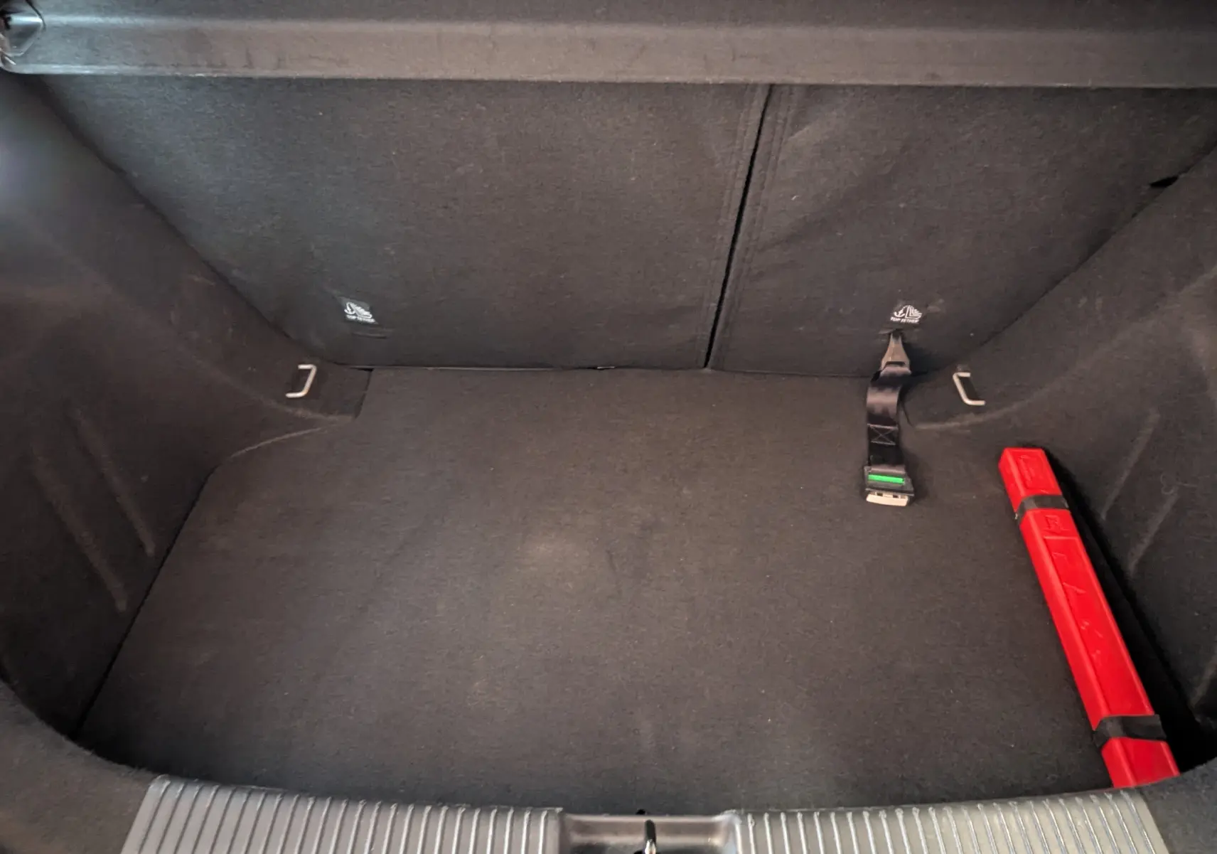 Coffre spacieux et vide du MG3 1.5 L Hybrid+ 195 ch Luxury, avec tapis noir et triangle de signalisation rouge.