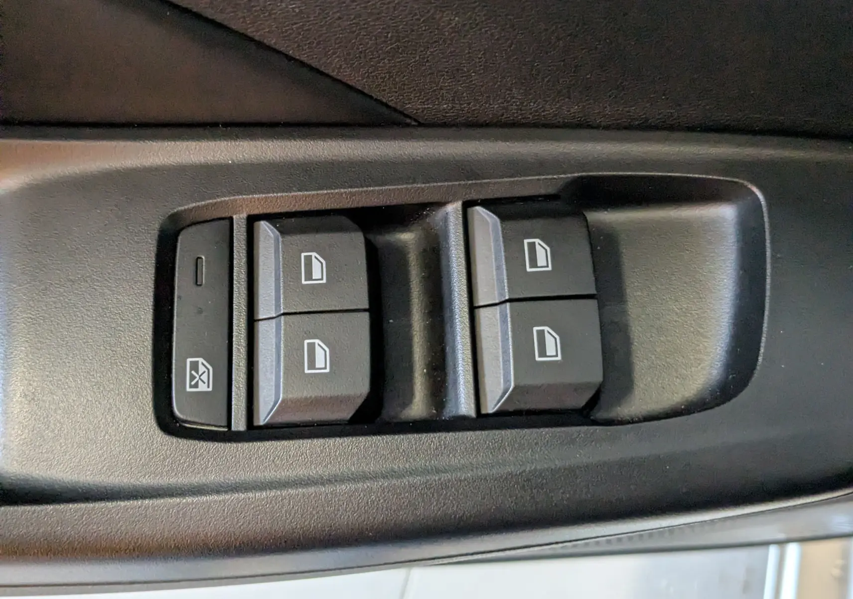 Gros plan sur les commandes de lève-vitres noires dans la portière côté conducteur du MG3 1.5 L Hybrid+ cosmic silver.