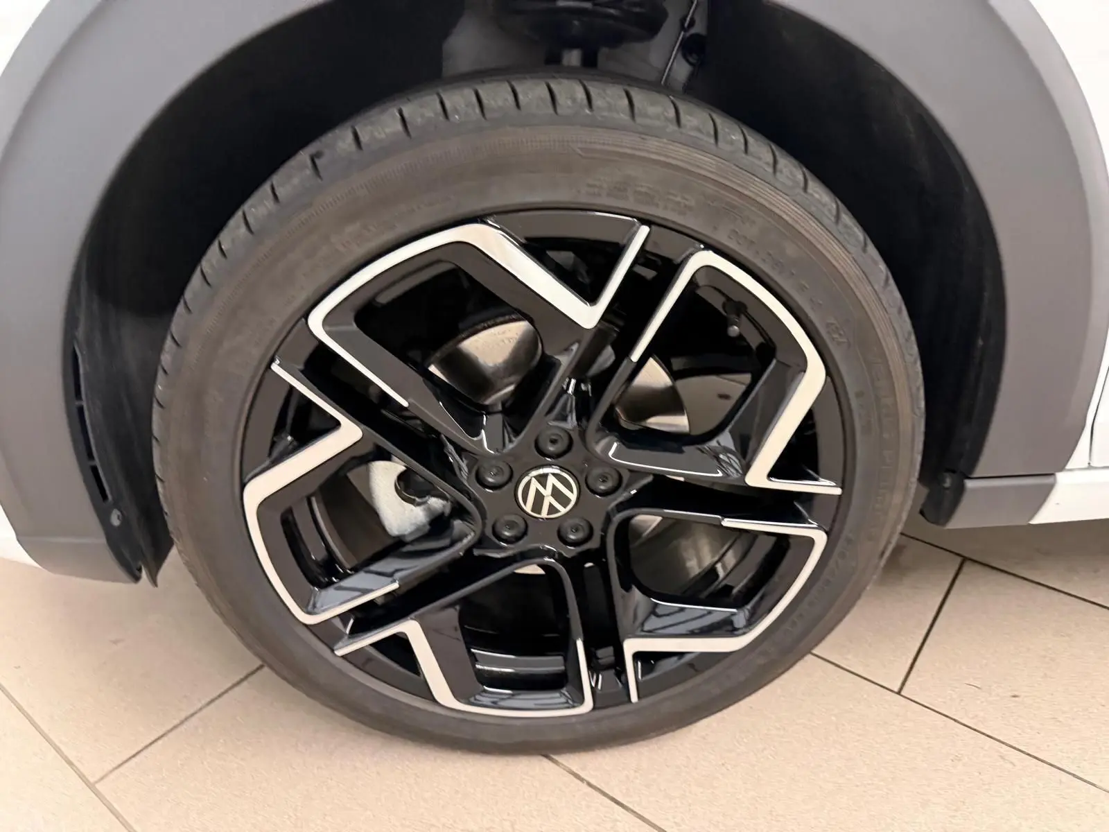 Gros plan sur la jante alliage noire et argentée du côté avant droit du Volkswagen Taigo blanc pur toit noir.