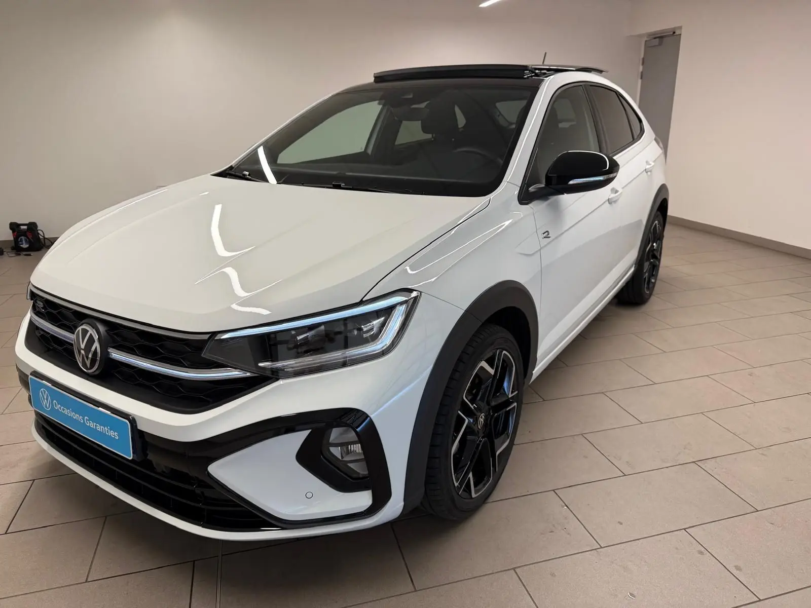 Volkswagen Taigo blanc pur toit noir en vue 3/4 avant droit, avec jantes alliage noires et calandre R-Line.