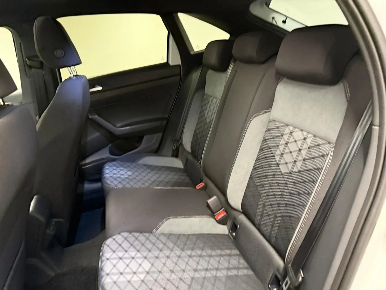 Vue intérieure côté gauche montrant la banquette arrière en tissu gris et noir avec motifs géométriques du Volkswagen Taigo 2025.