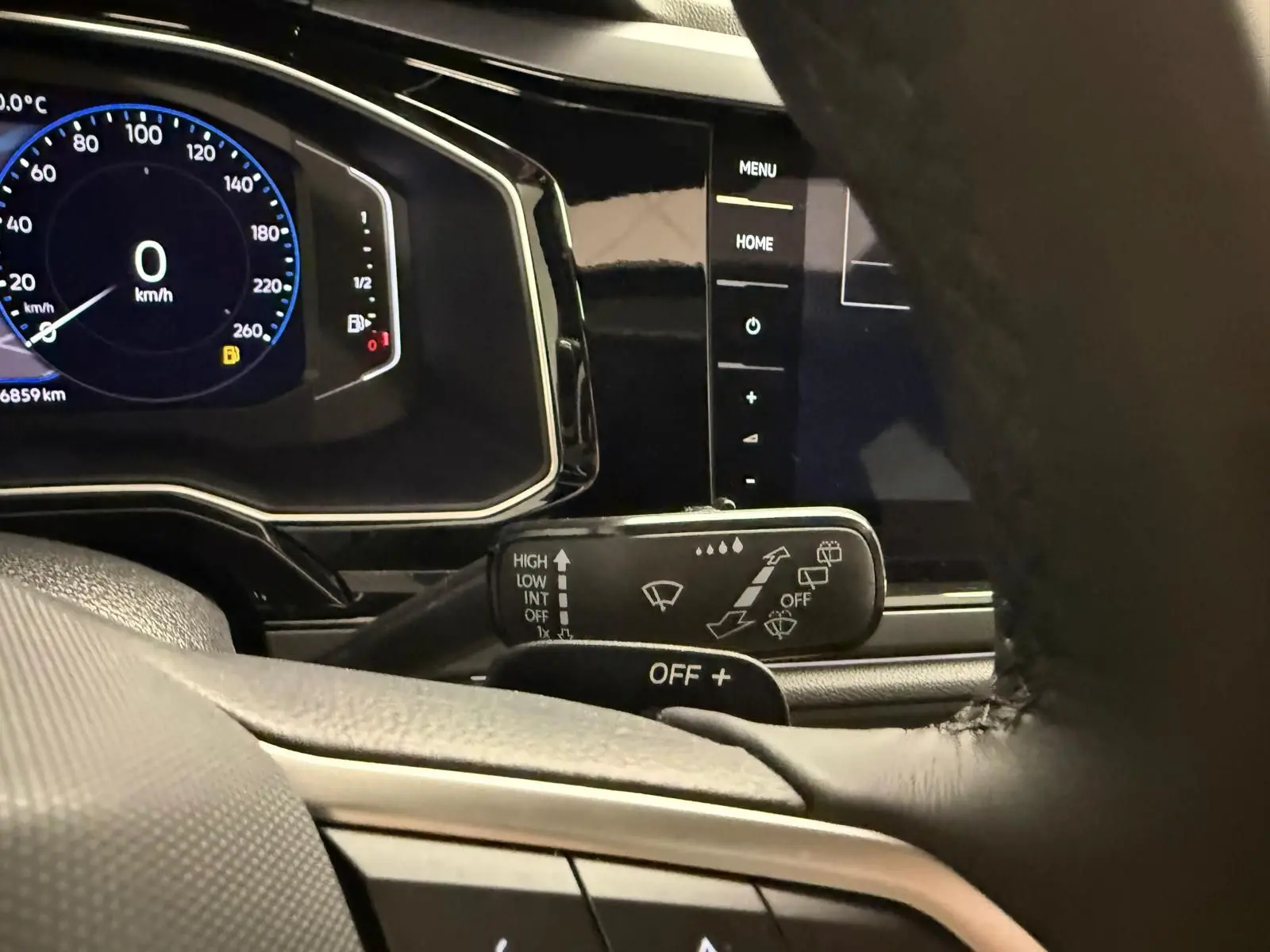 Vue rapprochée du tableau de bord et du commodo d'essuie-glace du Volkswagen Taigo 2025, intérieur noir.