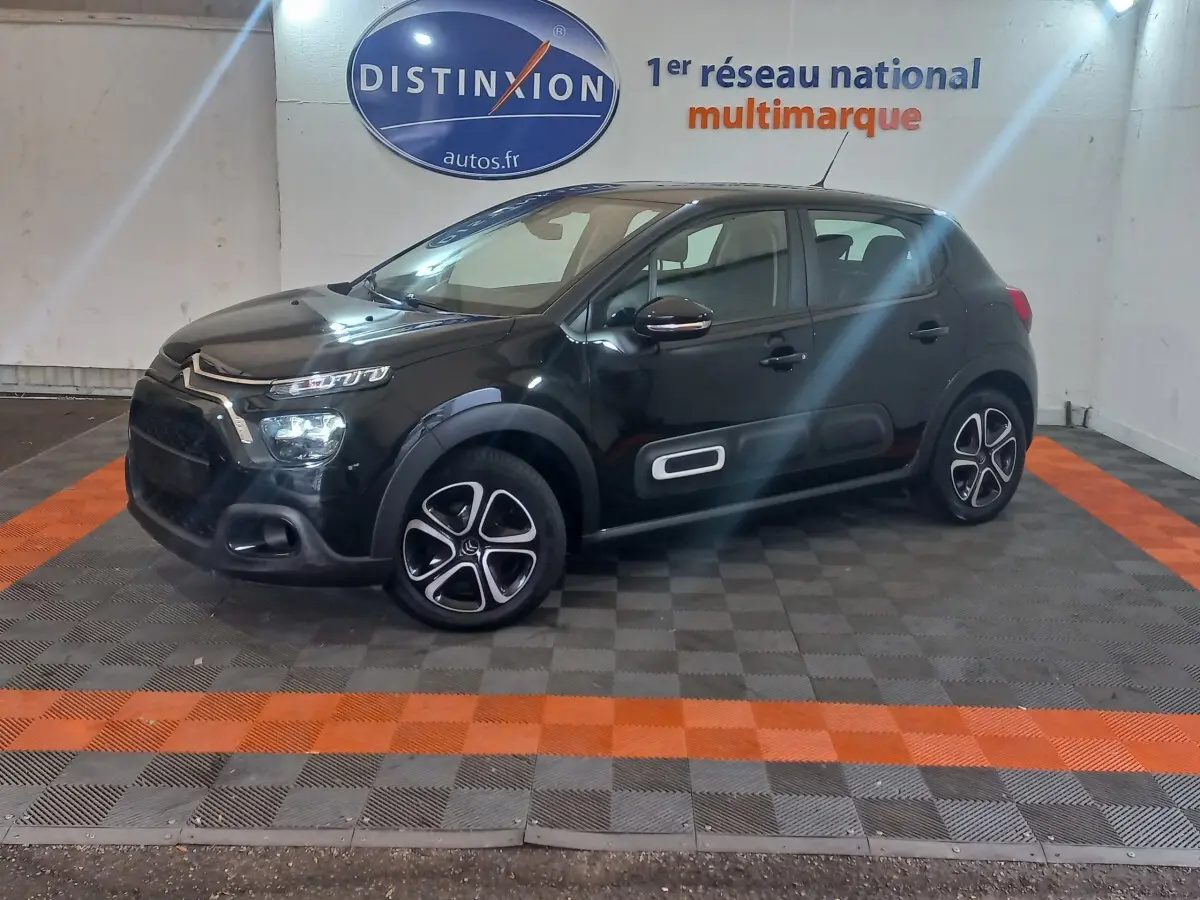 Citroën C3 BlueHDi 100 BVM PLUS noir vue de profil droit en intérieur, avec jantes distinctives et protections latérales blanches.