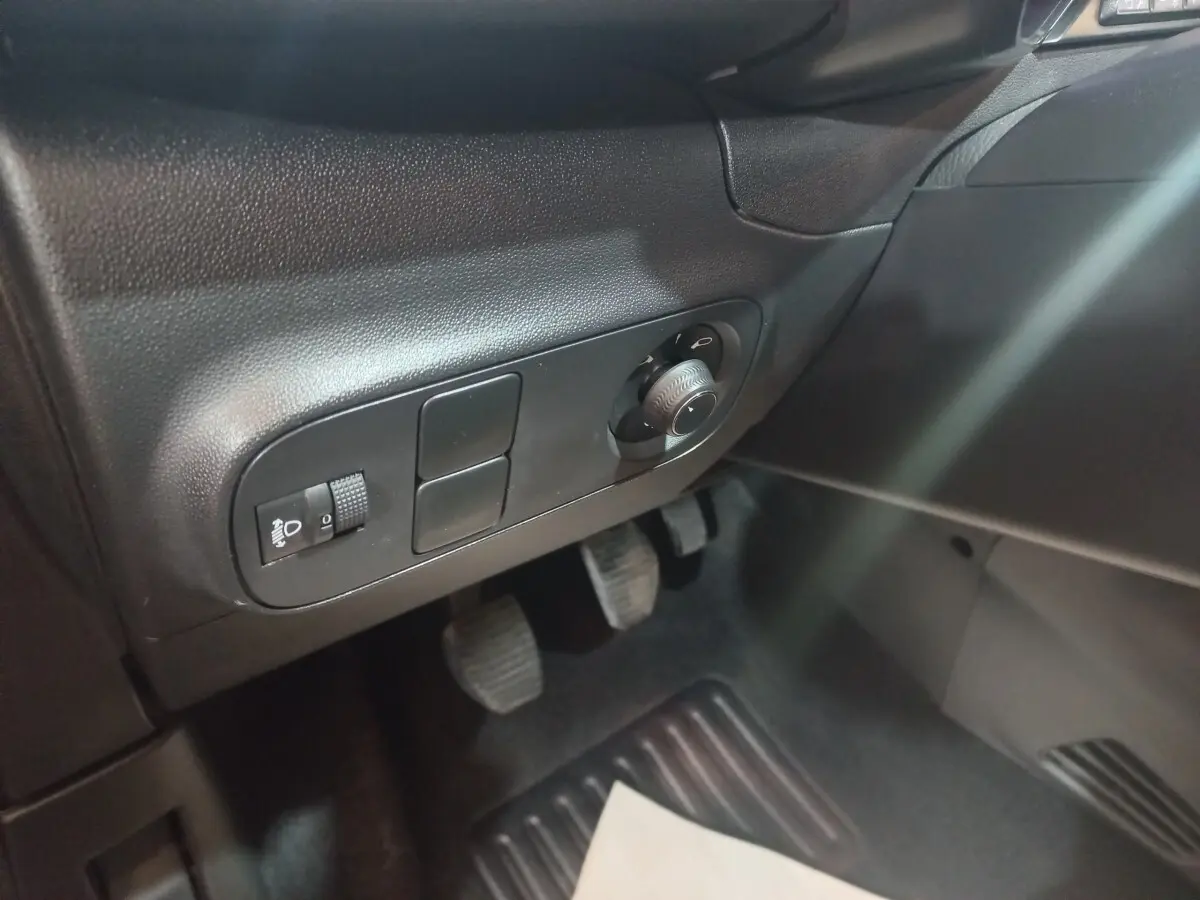 Détail du tableau de bord côté gauche noir avec commandes d’éclairage et pédales visibles dans une Citroën C3 2024.