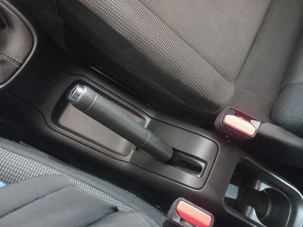 Vue rapprochée de la poignée de frein à main et des ceintures de sécurité noires à boutons rouges dans une Citroën C3 2024.