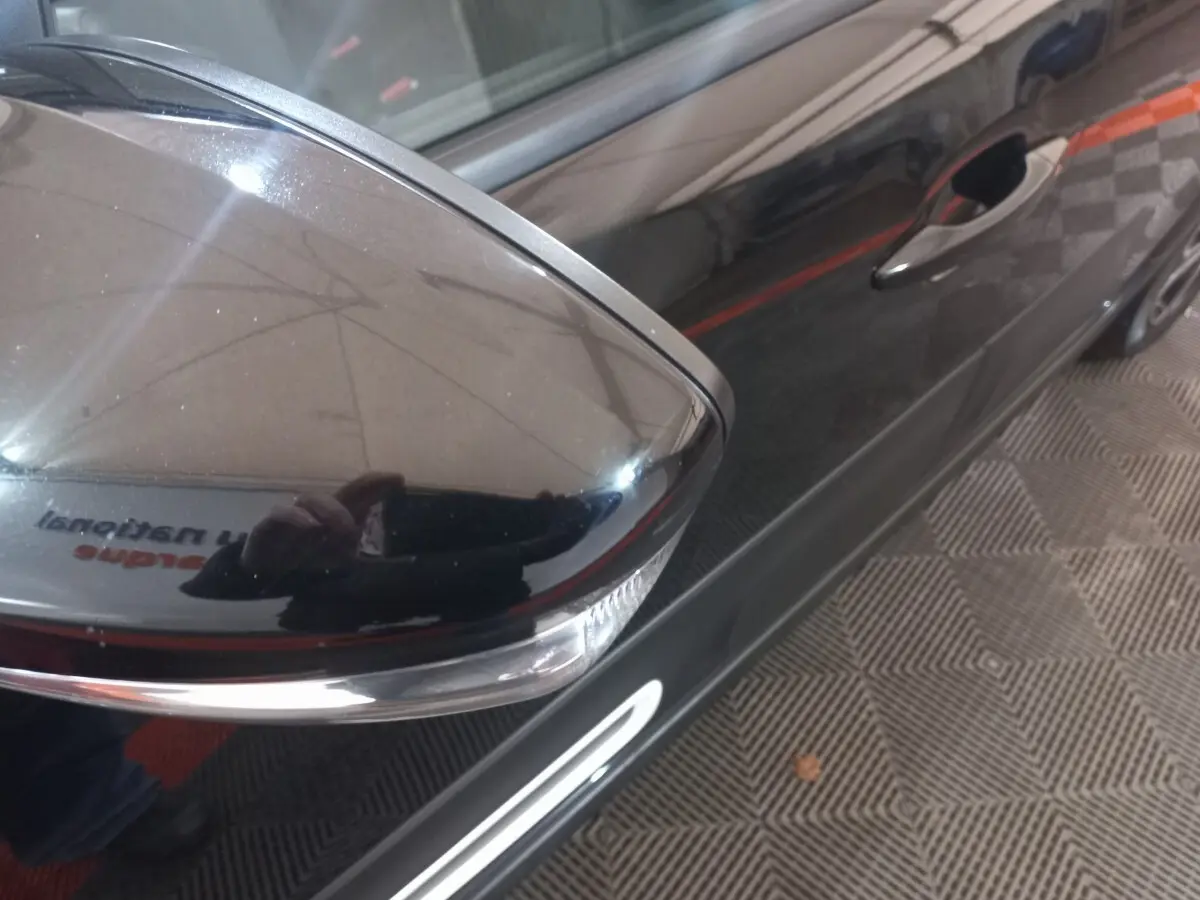 Gros plan sur le rétroviseur droit noir brillant de la Citroën C3 2024, avec reflet du photographe sur la porte.