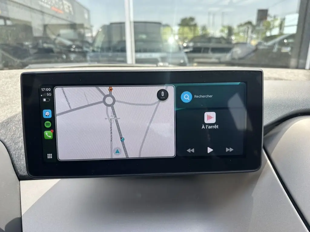 Écran tactile central affichant la navigation et la musique dans une BMW i3 noire, vue intérieure du tableau de bord.