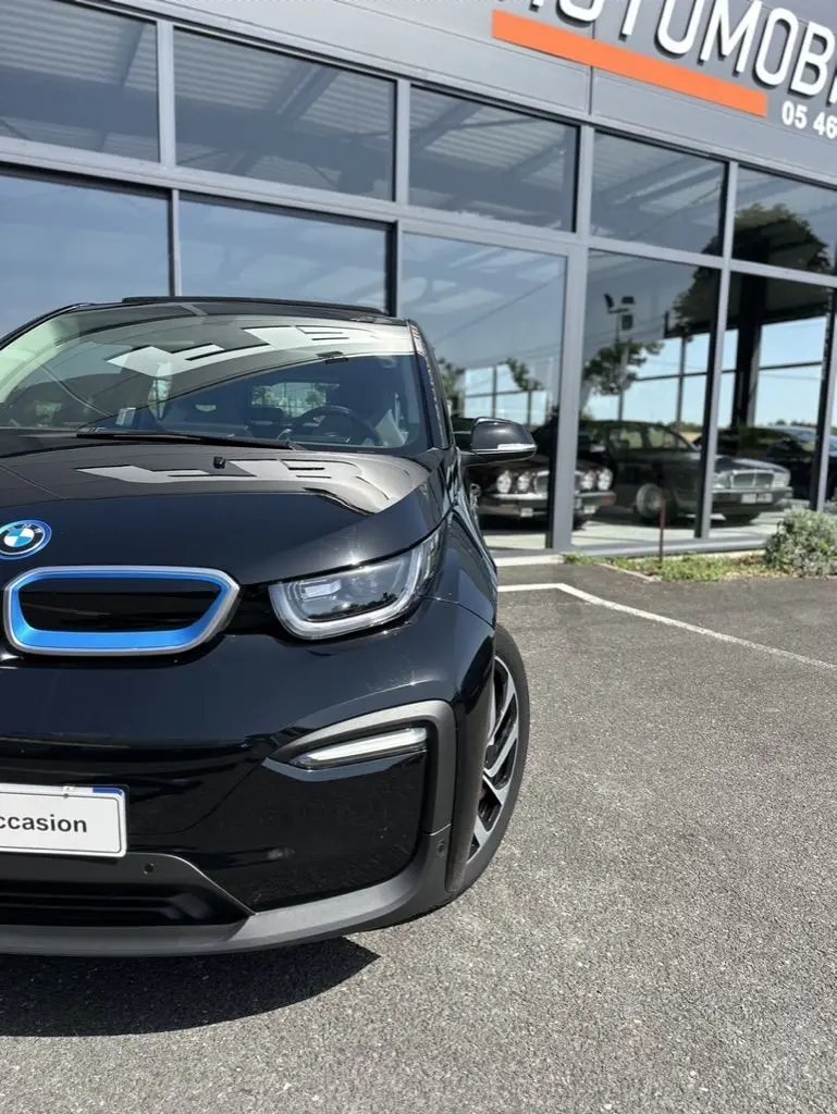Vue 3/4 avant droite d'une BMW i3 noire électrique 2022, avec calandre bleue distinctive et phares LED modernes.