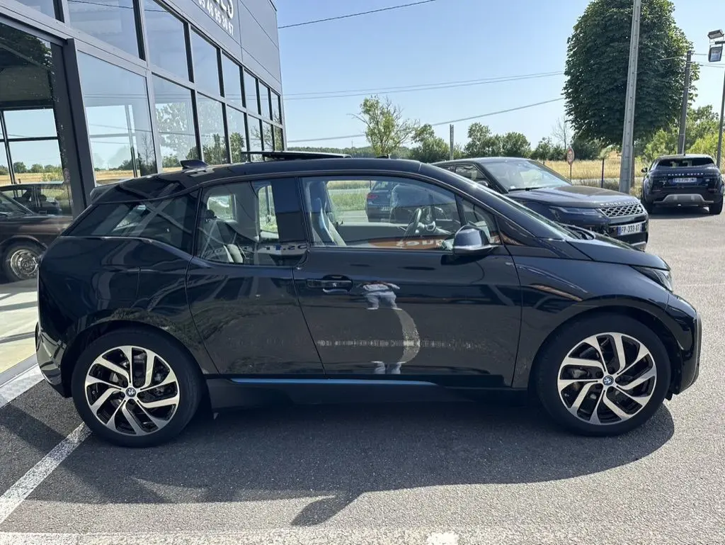 BMW i3 noire vue de profil côté gauche, mettant en valeur ses jantes distinctives et sa silhouette compacte électrique.