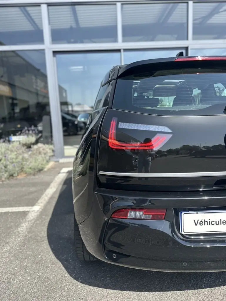 Vue arrière gauche d'une BMW i3 noire 2022, mettant en valeur les feux arrière LED distinctifs et la silhouette compacte électrique.