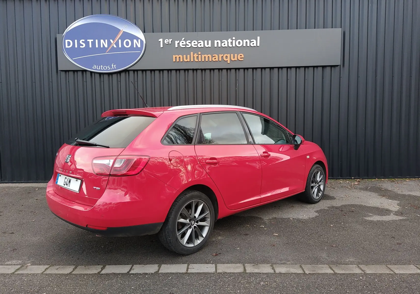 SEAT Ibiza ST rouge vue 3/4 arrière côté gauche, break compact avec jantes alliage et vitres teintées.