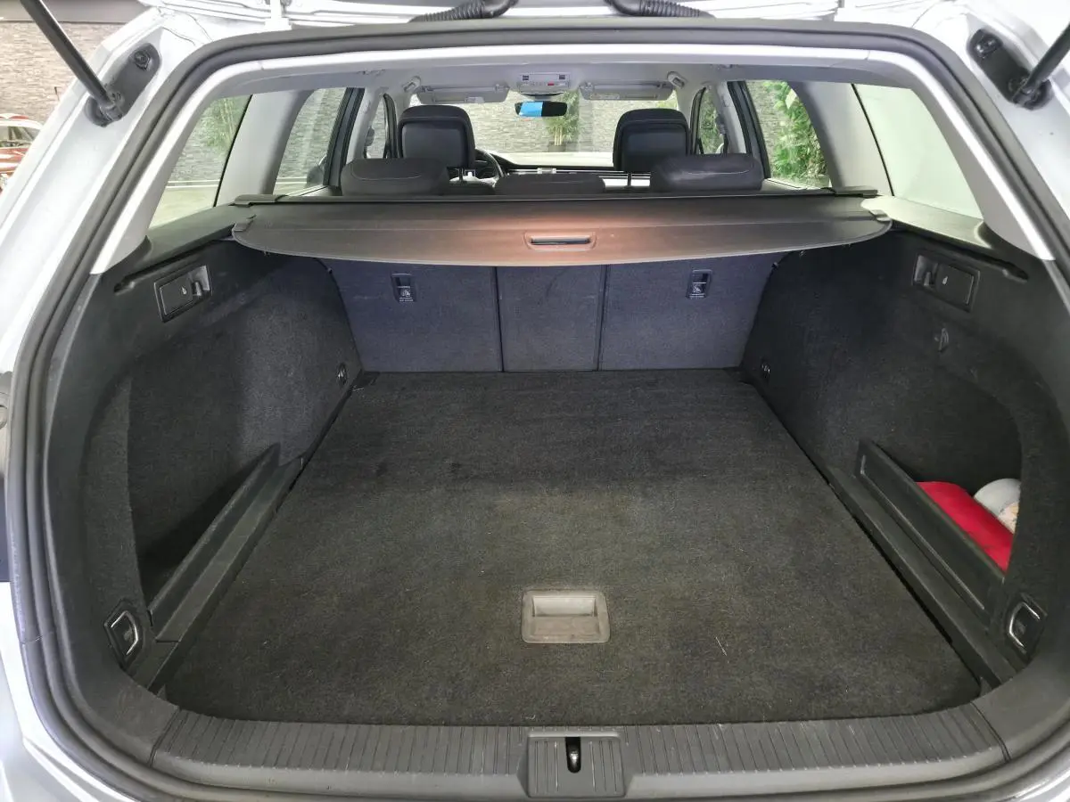 Coffre spacieux ouvert d'une Volkswagen Passat SW gris, avec cache-bagages et banquette arrière visible.