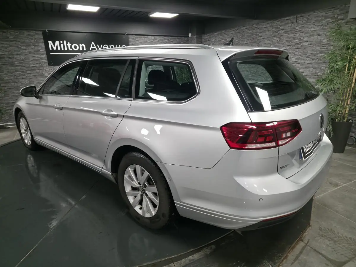 Vue 3/4 arrière droit d'une Volkswagen Passat SW gris métallisé en showroom avec feux arrière LED et jantes alliage.