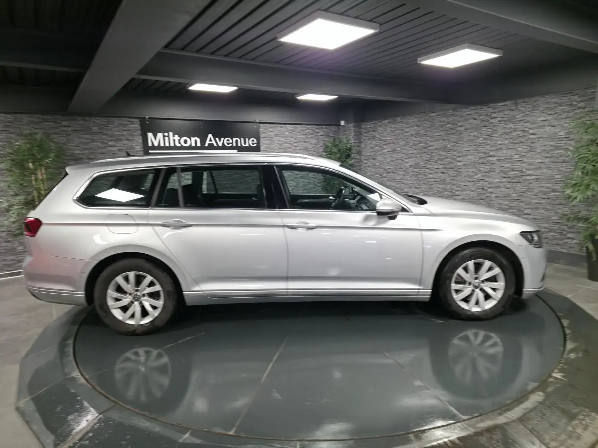 Volkswagen Passat SW gris métallisé vue de profil côté gauche dans un showroom intérieur moderne.