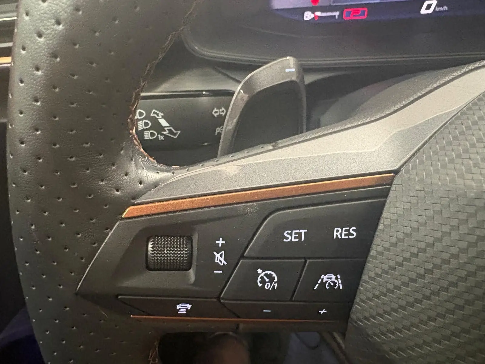 Gros plan sur les commandes du volant à gauche de la CUPRA Leon 2024, avec boutons de régulateur de vitesse et assistance à la conduite.