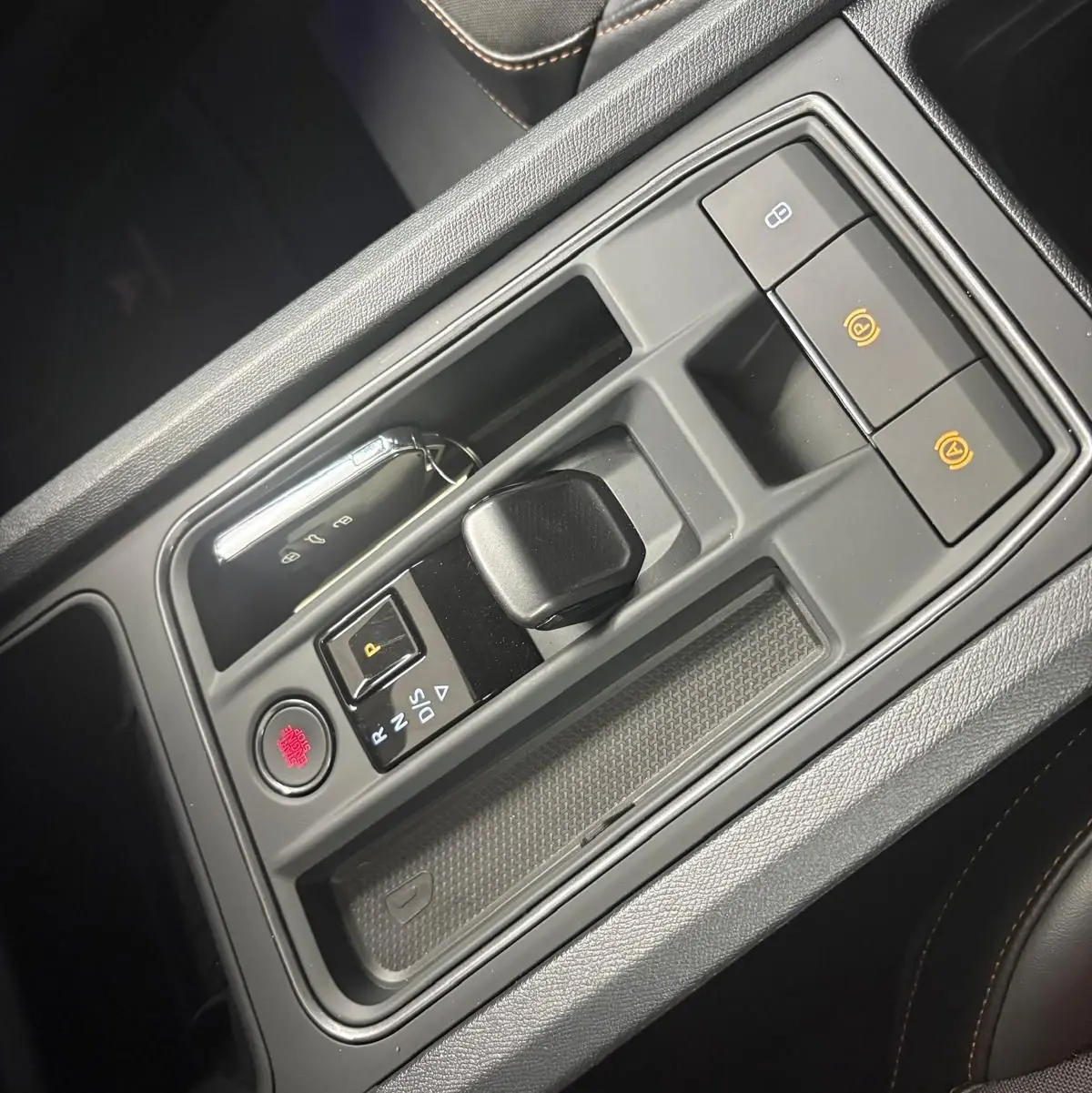 Vue rapprochée de la console centrale de la CUPRA Leon 2024, avec levier de vitesse compact et bouton de démarrage rouge.