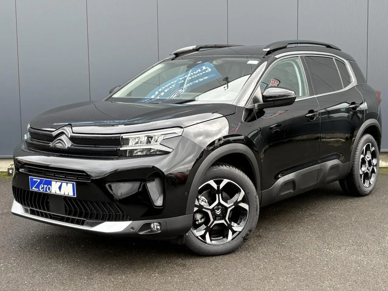 Vue 3/4 avant droite du Citroën C5 Aircross 2025 noir Perla avec jantes diamantées et barres de toit noires.
