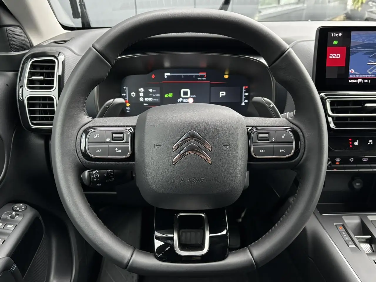 Vue intérieure centrée sur le volant cuir noir du Citroën C5 Aircross 2025 avec tableau de bord numérique et écran tactile.