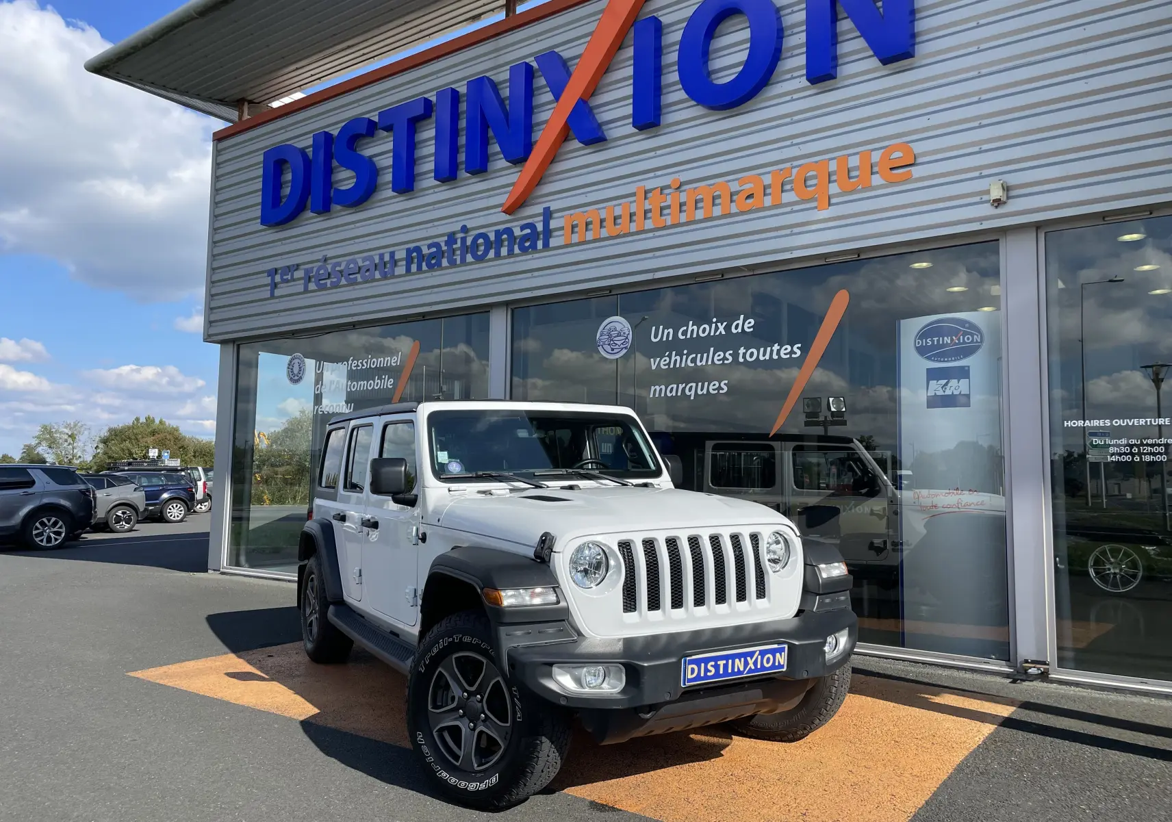 Jeep Wrangler blanc vu de face à 3/4 gauche, avec calandre à sept fentes et jantes noires distinctives.