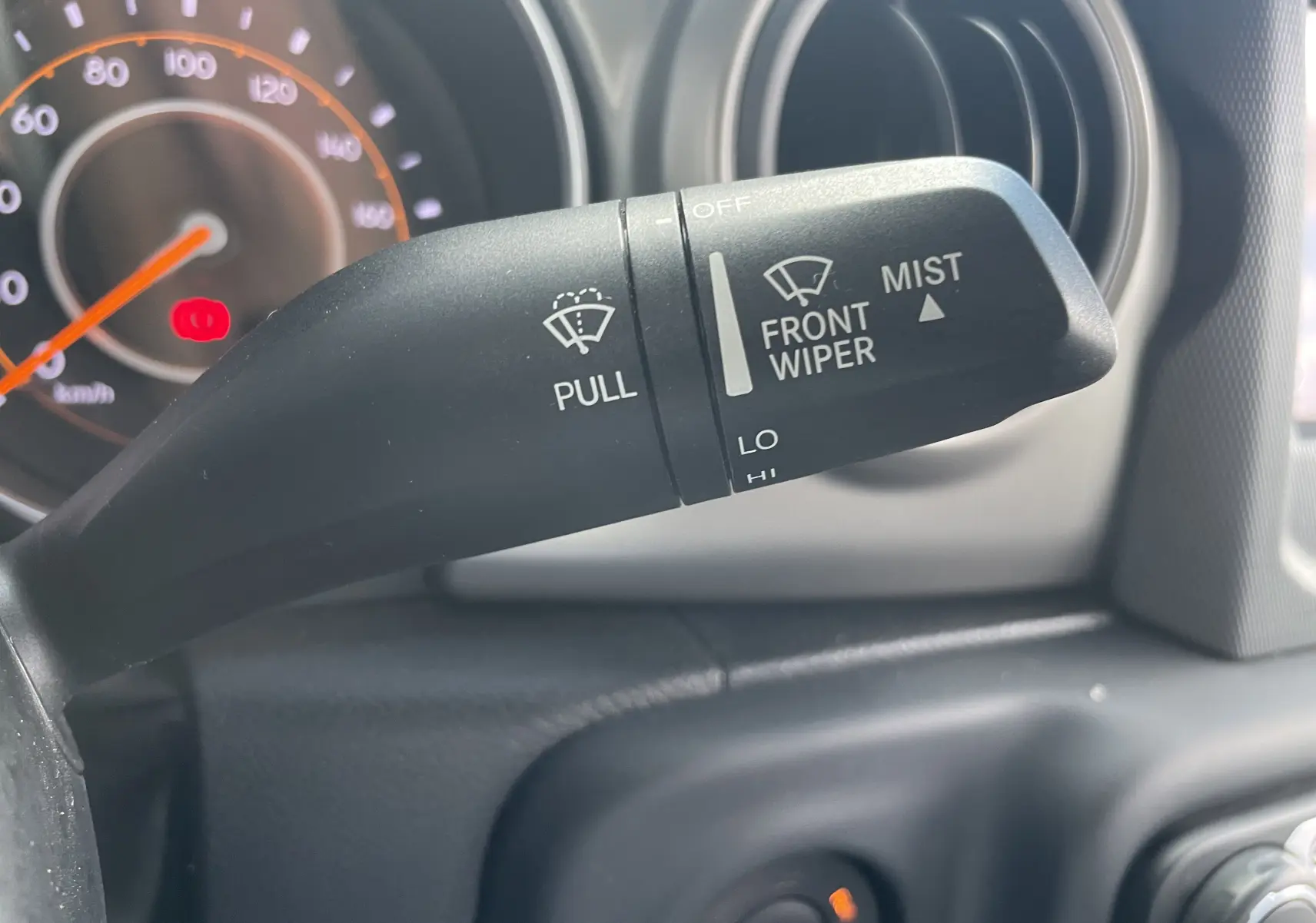 Le levier d'essuie-glace noir en gros plan dans l'habitacle d'une Jeep Wrangler blanche de 2018.