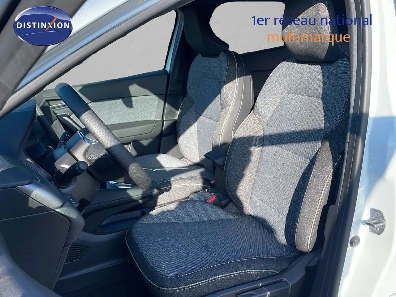 Intérieur avant droit du Renault Captur E-Tech hybride 2025 avec sièges tissu gris et volant noir.