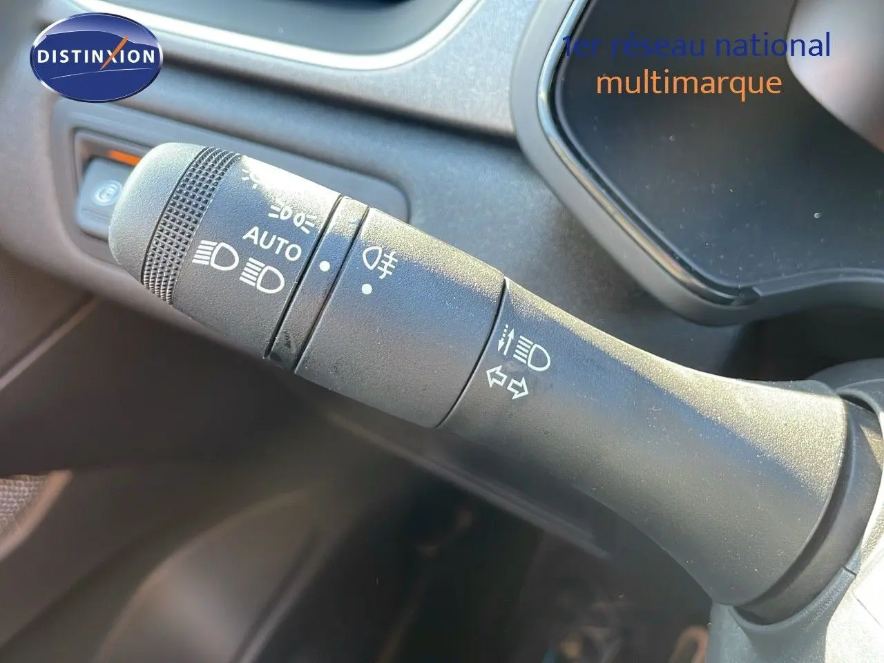 Le commodo d'éclairage du Renault Captur blanc nacré, avec commandes pour feux et clignotants, en gros plan intérieur.