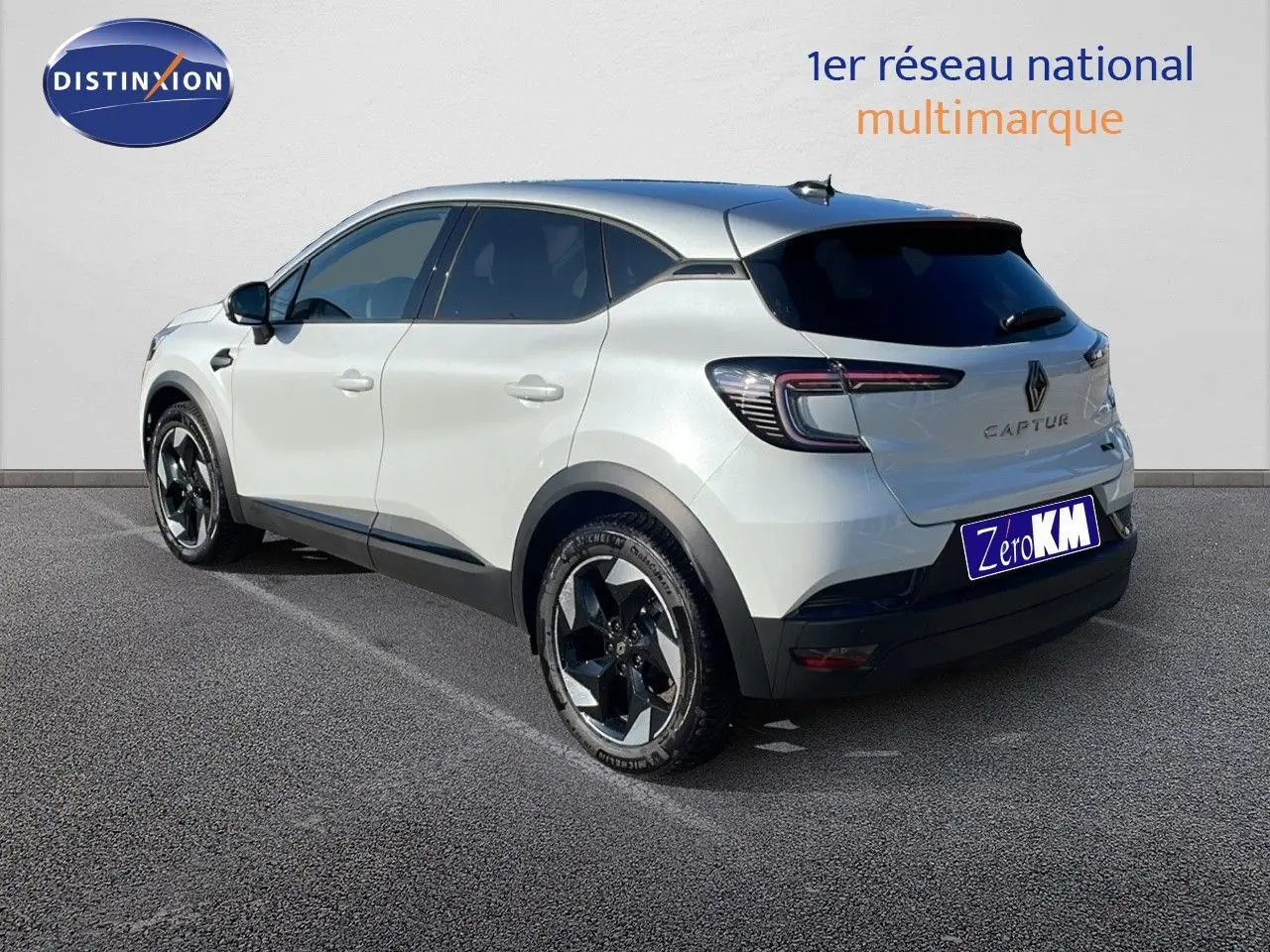 Vue 3/4 arrière droite d'un Renault Captur blanc nacré avec toit gris, soulignant ses jantes noires et son design moderne.