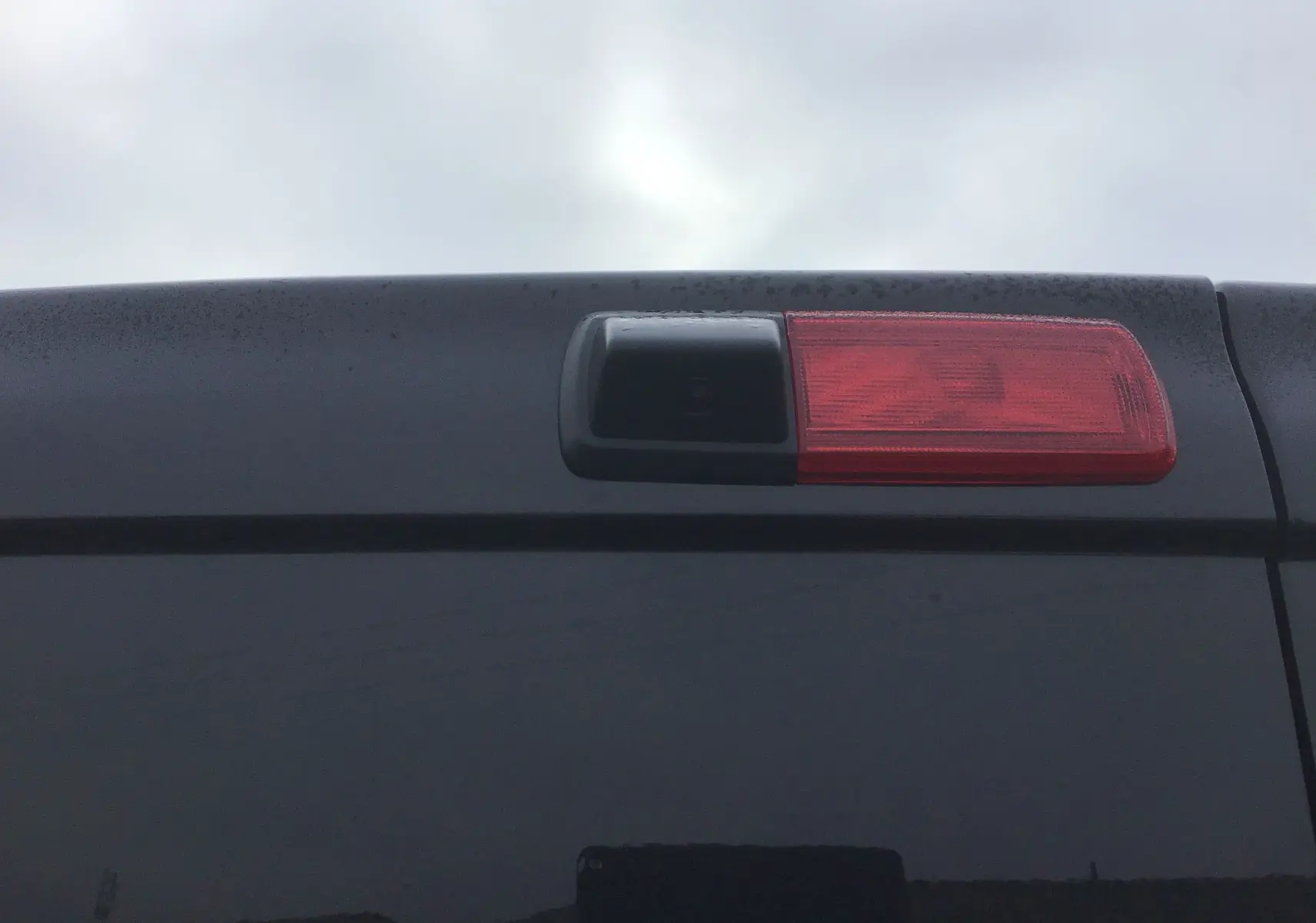 Gros plan sur la caméra de recul intégrée au feu stop arrière du Renault Trafic Fourgon noir, version 2025.