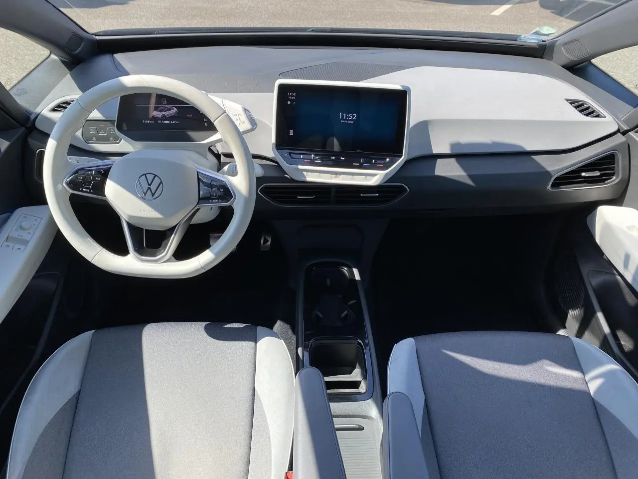 Intérieur du Volkswagen ID.3 Pro Performance vu de dessus, tableau de bord clair et sièges tissu gris avec accoudoirs.