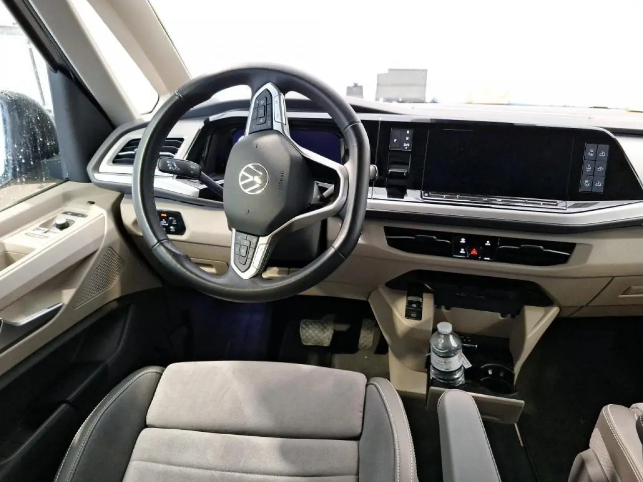 Vue intérieure avant du Volkswagen California T7 2.0 TDI gris, volant cuir multifonctions et tableau de bord numérique.