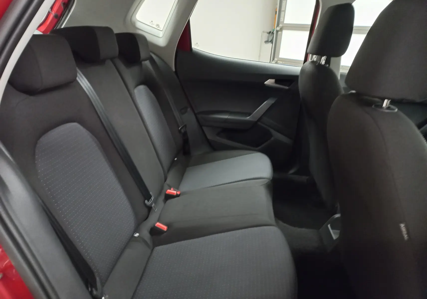 Vue intérieure arrière côté gauche des sièges arrière noirs du SEAT Arona 2025, tissu et ceintures visibles.