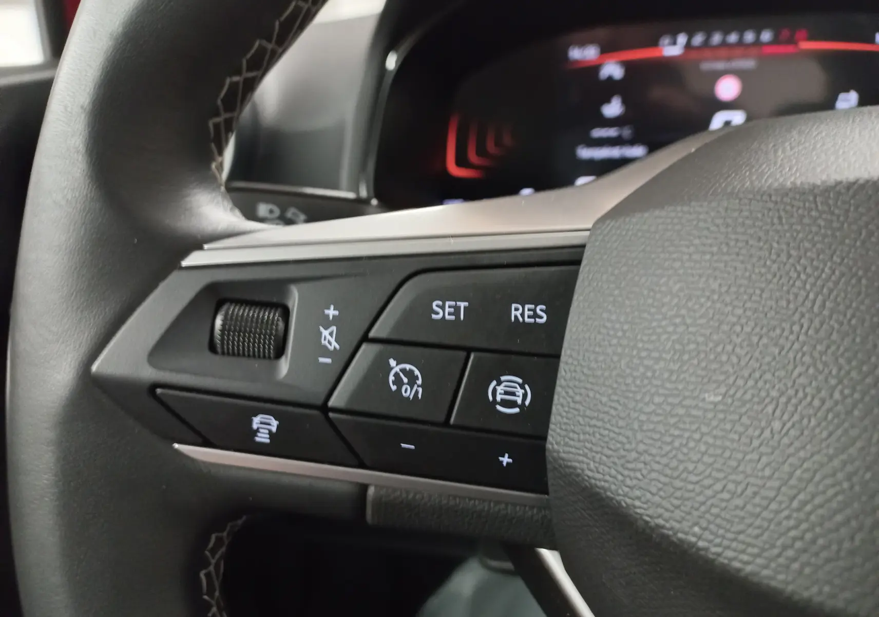 Gros plan sur les commandes au volant côté gauche du SEAT Arona 2025, boutons du régulateur de vitesse adaptatif et assistant de conduite.