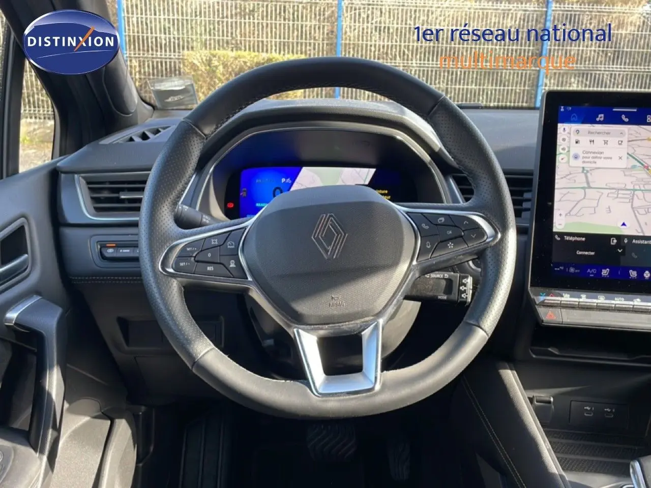 Vue intérieure centrée sur le volant du Renault Symbioz gris cassiopée, avec tableau de bord numérique et écran tactile visible.