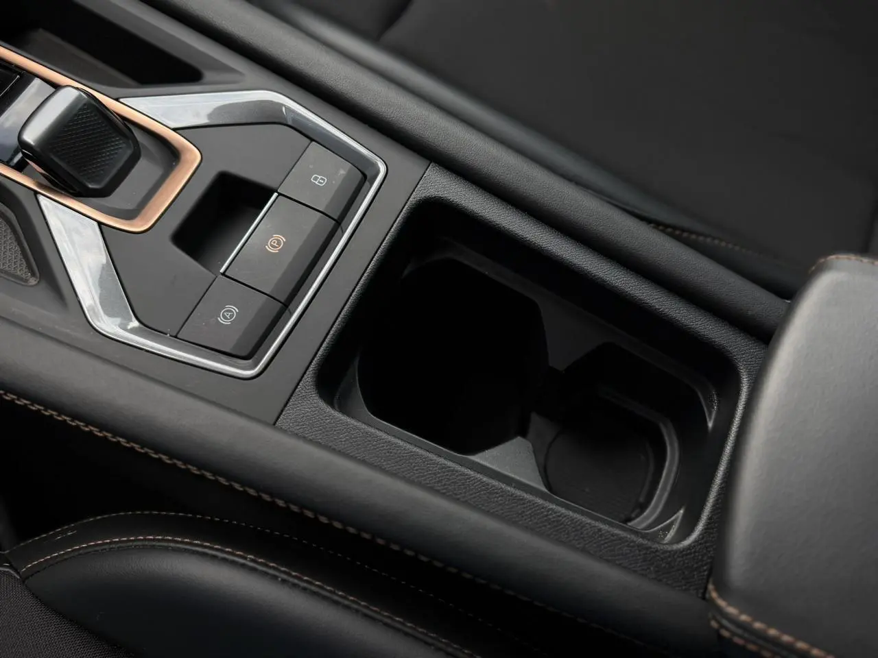 Gros plan sur la console centrale noire avec commandes électroniques et accoudoir en cuir surpiqué marron du CUPRA Formentor.