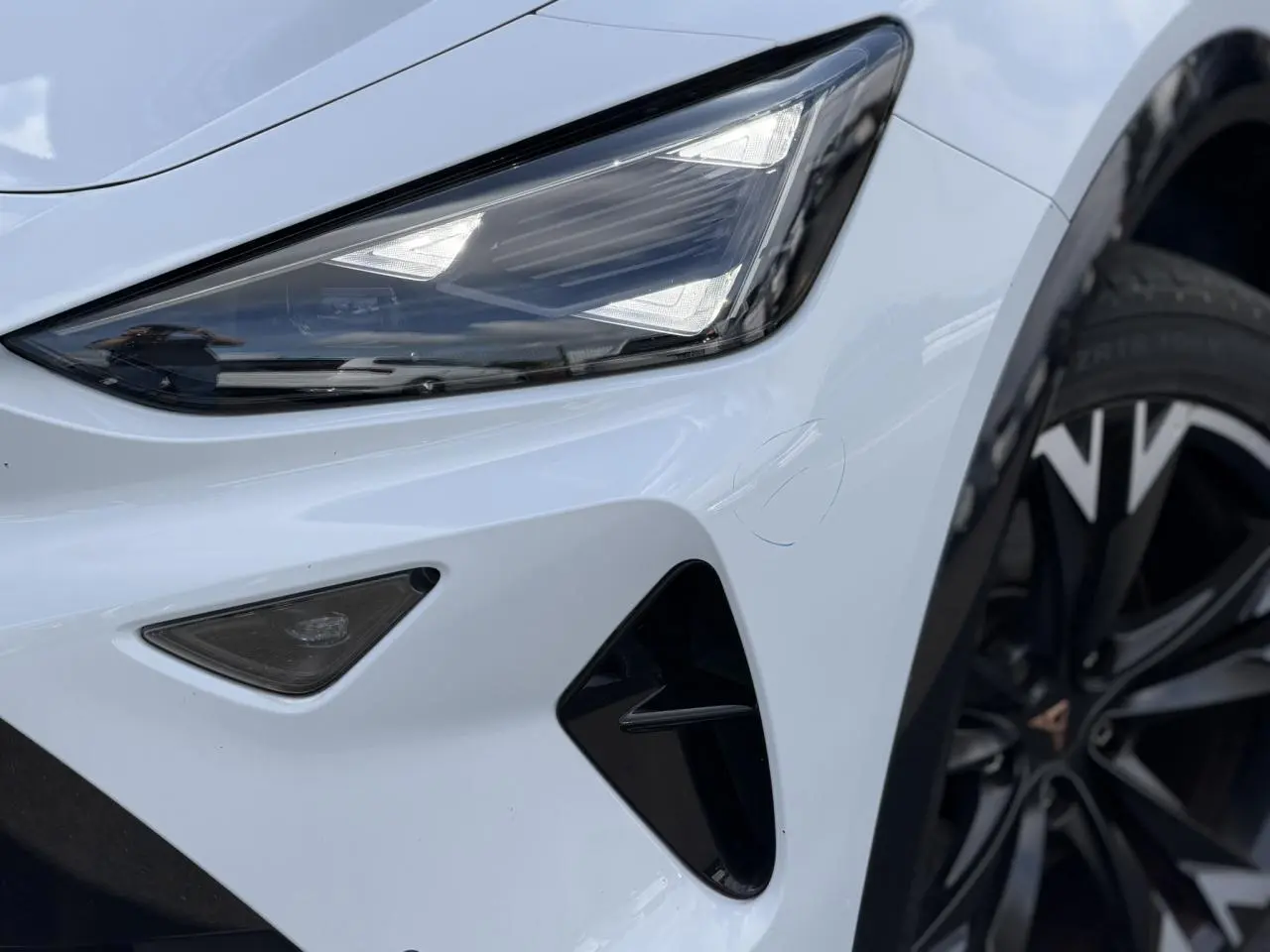 Gros plan sur le phare avant gauche blanc Neige du CUPRA Formentor 2025 avec jante alliage noire et détails noirs contrastants.