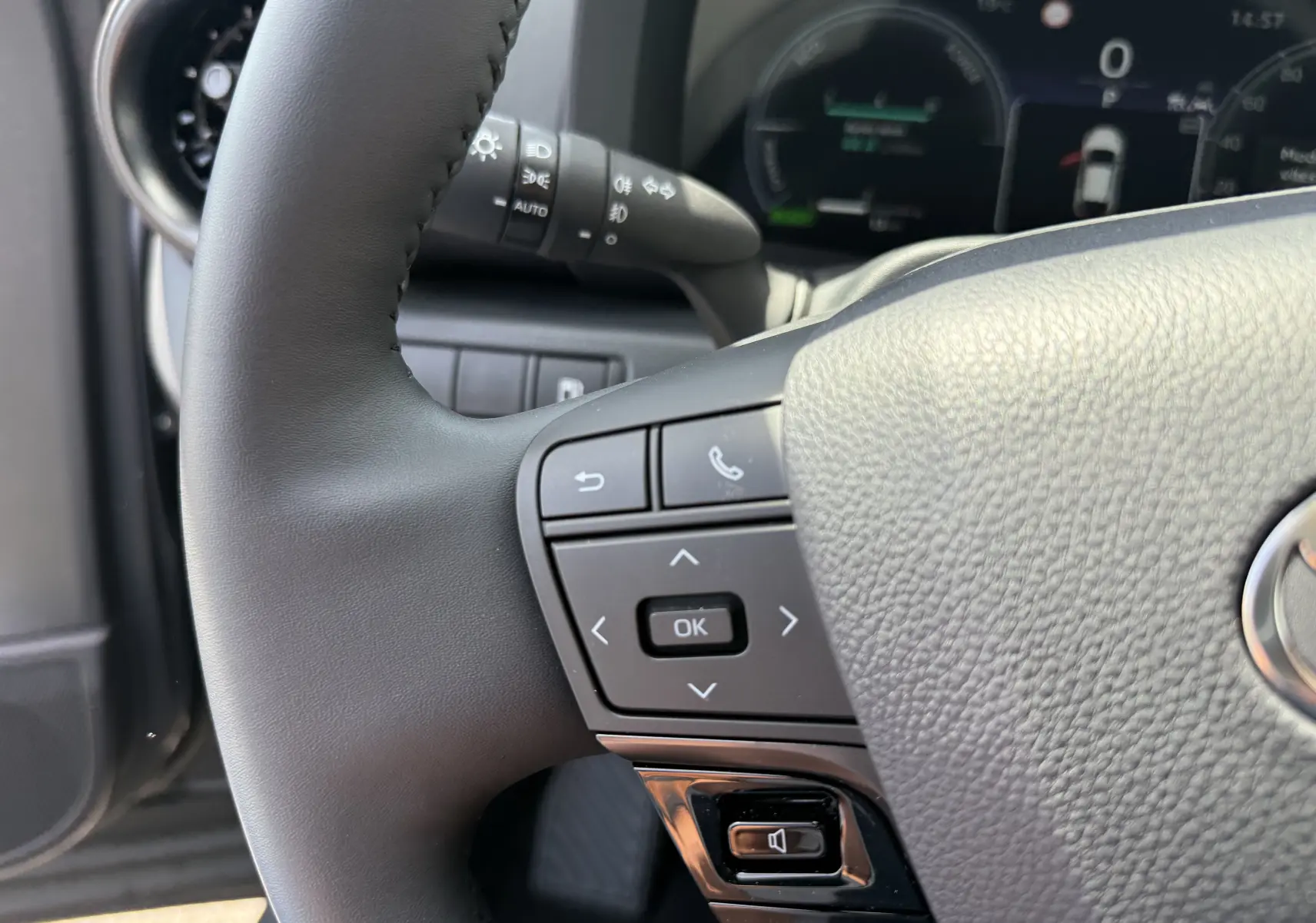 Gros plan sur le volant noir du Toyota C-HR 1.8 Hybride 140 Style 2025 avec commandes intégrées et tableau de bord numérique flou.