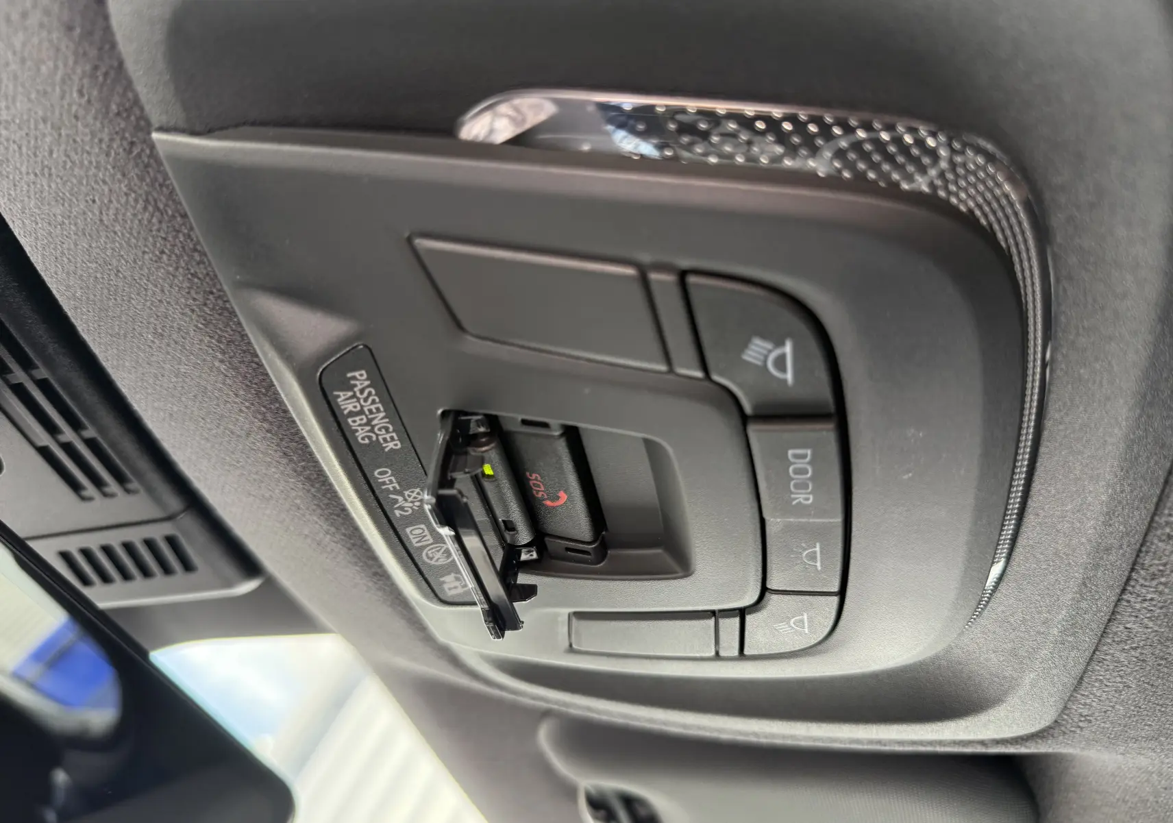 Vue en gros plan du panneau de commandes au plafond avec bouton SOS et indicateur airbag passager du Toyota C-HR gris atlas 2025.