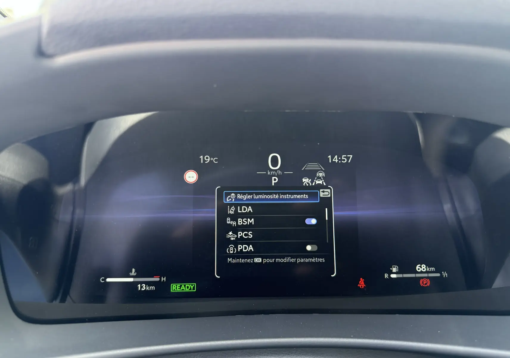 Affichage numérique du tableau de bord du Toyota C-HR 1.8 Hybride 2025 avec menu réglage luminosité et indicateurs actifs.