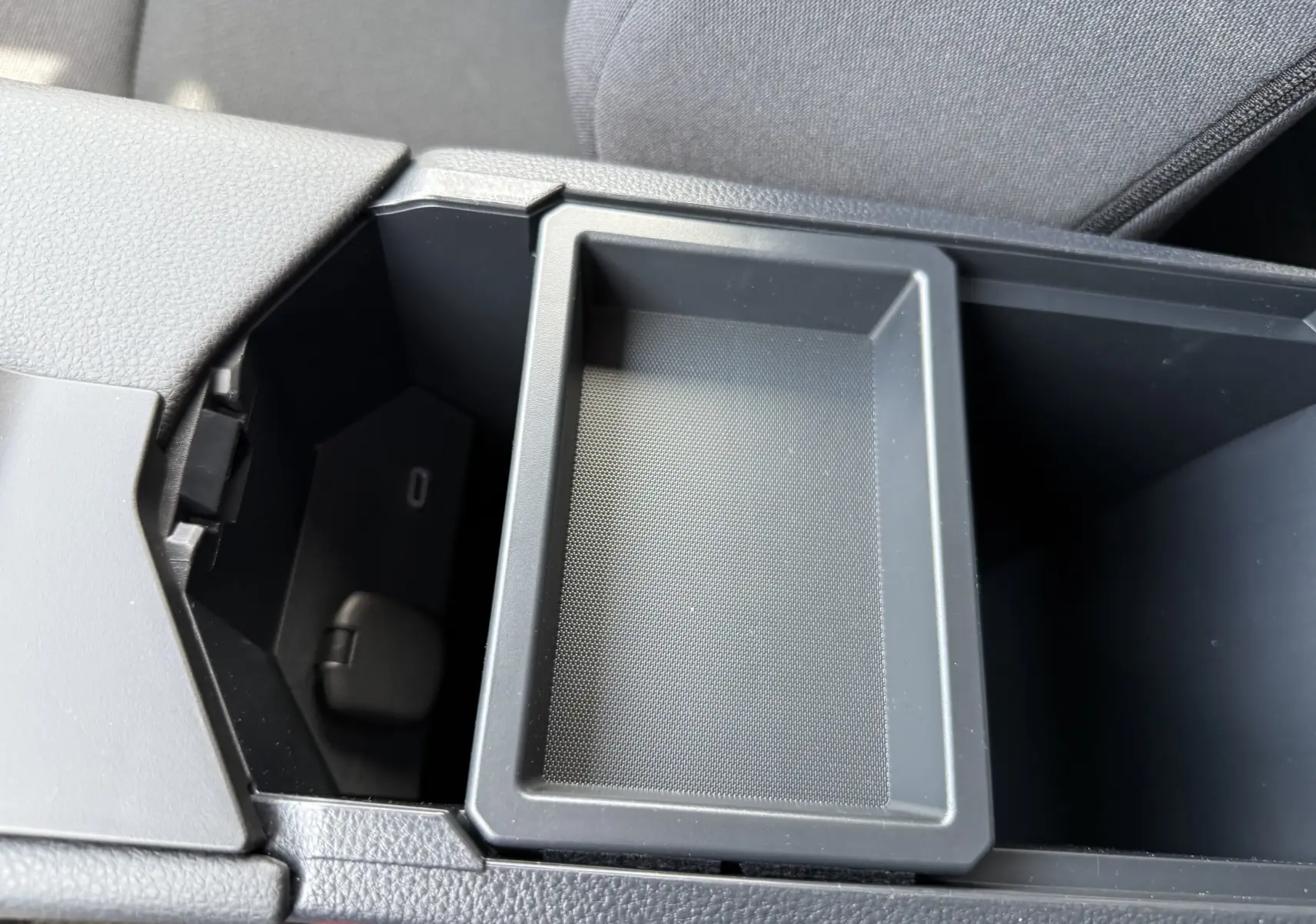 Rangement central ouvert avec plateau amovible et siège conducteur en tissu gris dans Toyota C-HR 1.8 Hybride 2025.