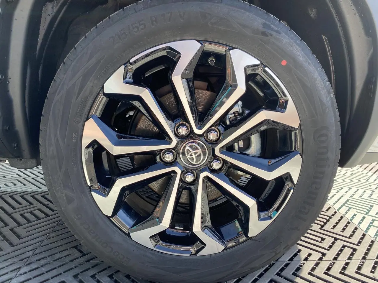 Gros plan sur la jante alliage 17'' bicolore noir et argent du Toyota Yaris Cross blanc pure, avec logo Toyota central.