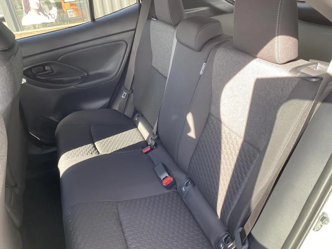 Vue intérieure côté droit des sièges arrière en tissu gris de la Toyota Yaris Cross 2025 blanche.