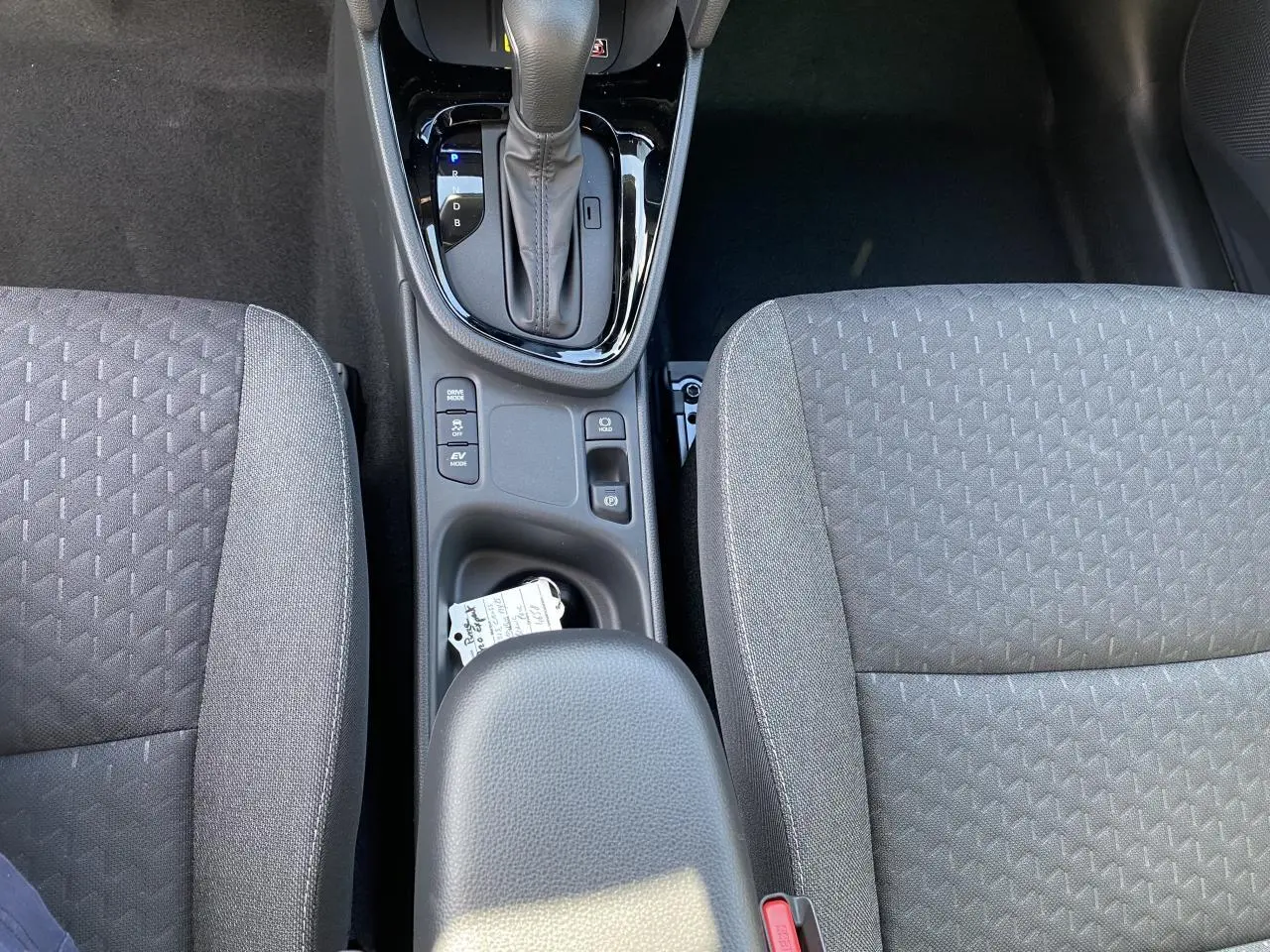 Vue plongeante sur la console centrale et les sièges gris en tissu du Toyota Yaris Cross hybride 2025.
