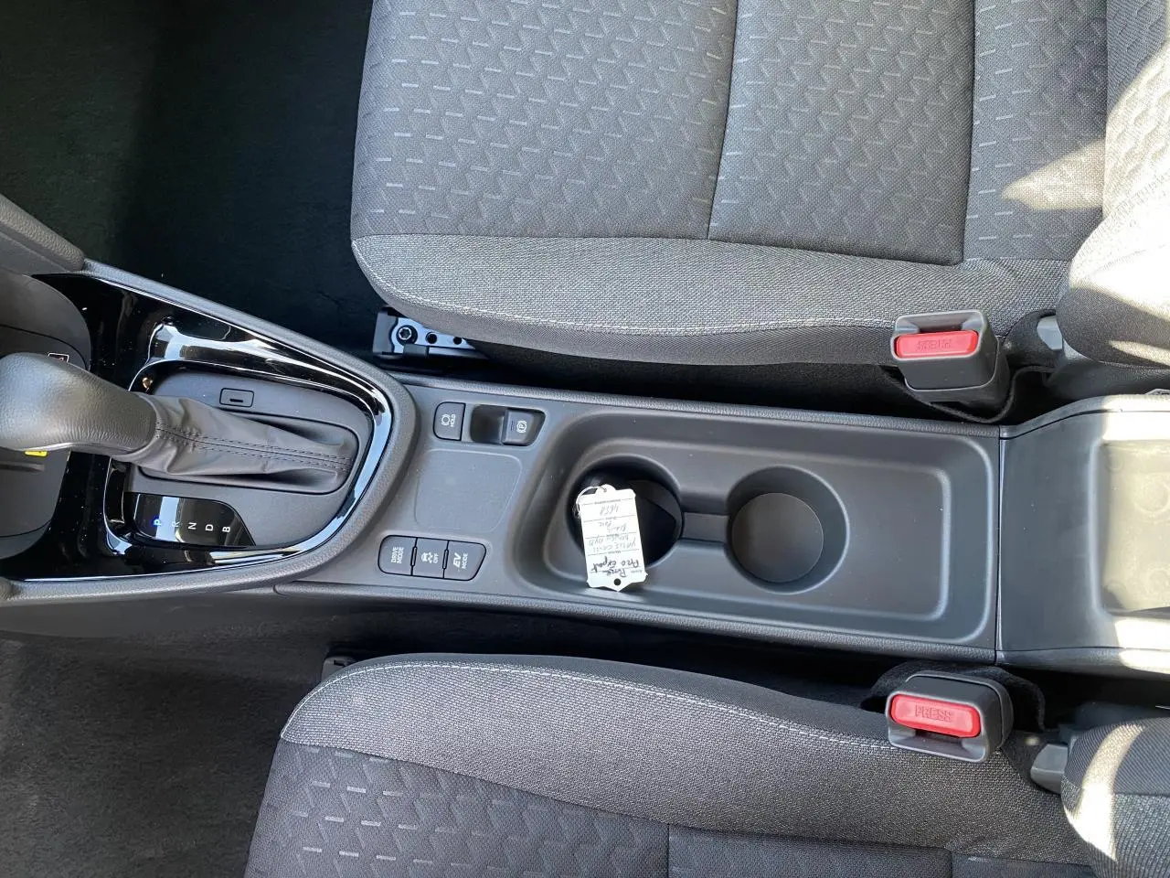 Vue plongeante sur la console centrale et la boîte auto d'une Toyota Yaris Cross blanche, avec sièges tissu gris.